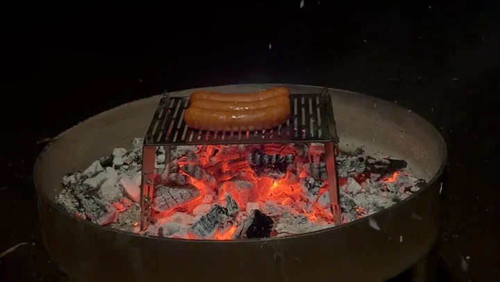 Der Flambini-Lagerfeuergriller im Einsatz über glühender Kohle